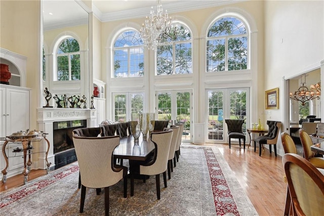 sunroom featuring a high end fireplace, an inviting chandelier, french doors, and a wealth of natural light