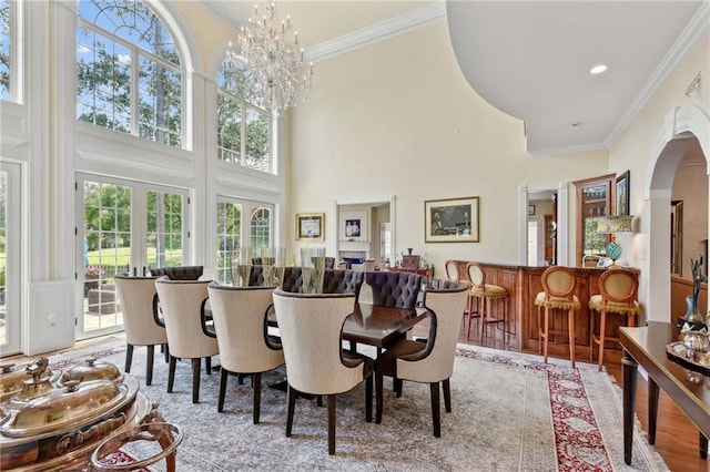 dining space featuring a high ceiling, an inviting chandelier, light wood-type flooring, and crown molding