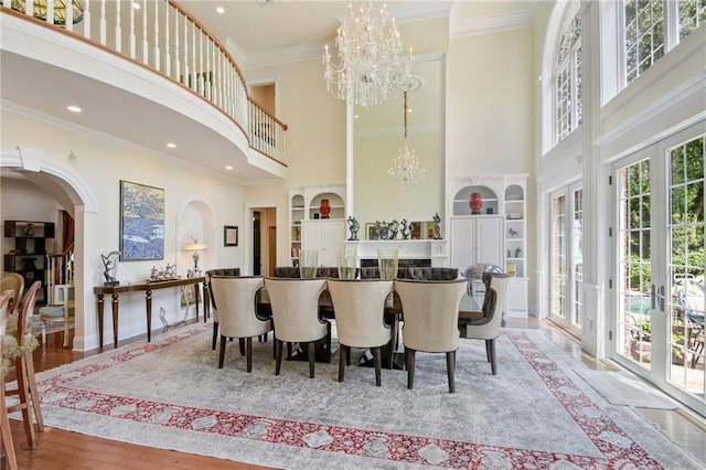 dining area with a towering ceiling, built in features, french doors, and crown molding