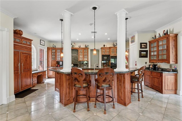 kitchen with decorative light fixtures, kitchen peninsula, decorative columns, and a breakfast bar