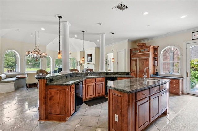 kitchen featuring decorative light fixtures, a notable chandelier, ornate columns, a kitchen island with sink, and sink