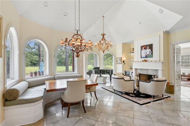 tiled dining space featuring a high end fireplace, high vaulted ceiling, a notable chandelier, and a healthy amount of sunlight