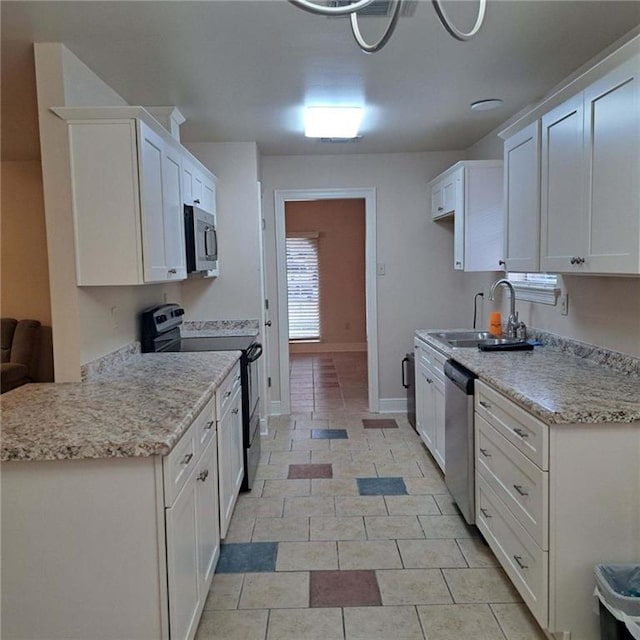 kitchen with white cabinetry, appliances with stainless steel finishes, light stone counters, sink, and light tile floors