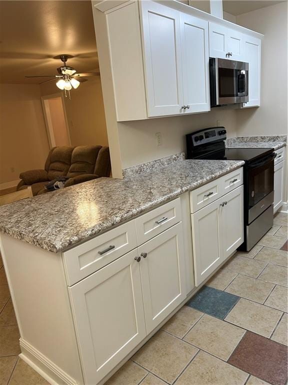 kitchen with light stone counters, light tile flooring, ceiling fan, white cabinetry, and appliances with stainless steel finishes