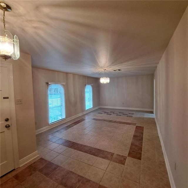 empty room with an inviting chandelier and tile floors