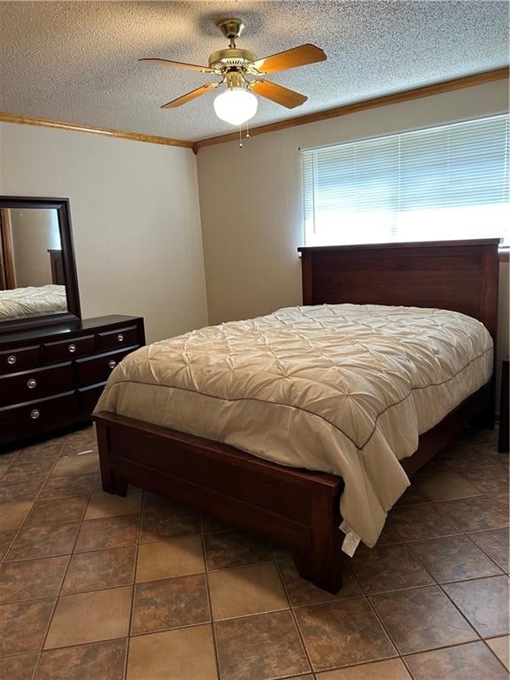 tiled bedroom featuring ornamental molding, ceiling fan, and a textured ceiling