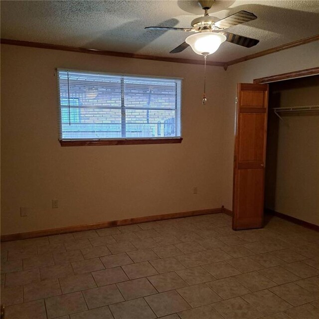 unfurnished bedroom with tile floors, ceiling fan, a closet, and crown molding