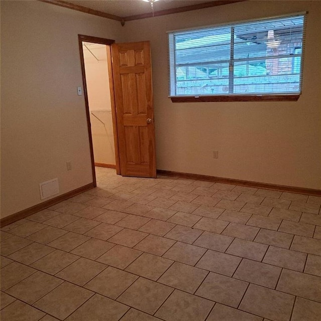 tiled spare room with crown molding