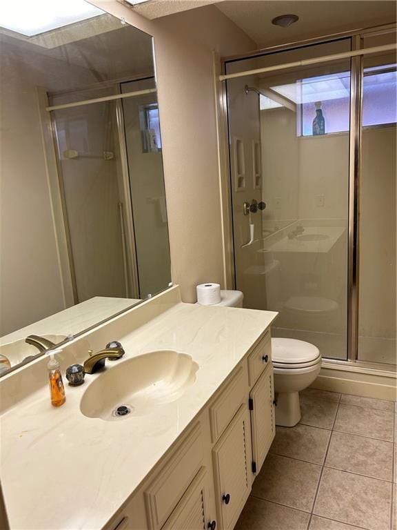 bathroom with vanity, toilet, tile floors, and a shower with door