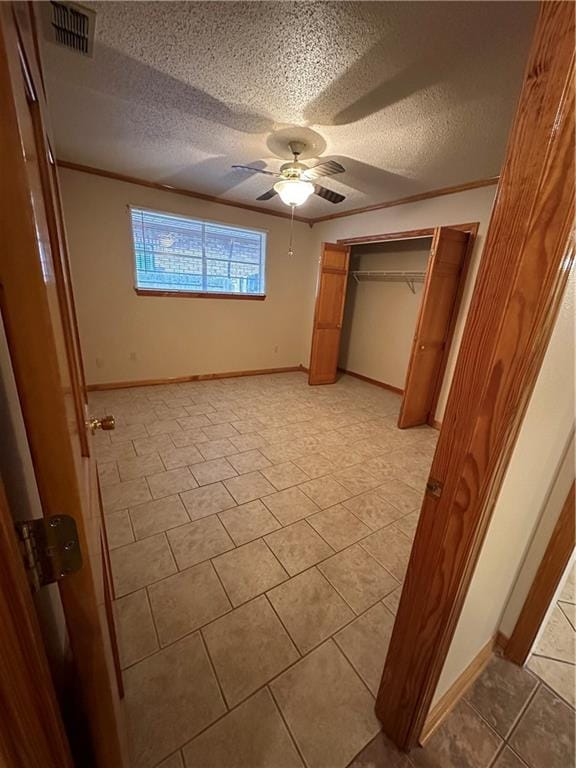 unfurnished bedroom featuring ceiling fan, a closet, a textured ceiling, and light tile floors