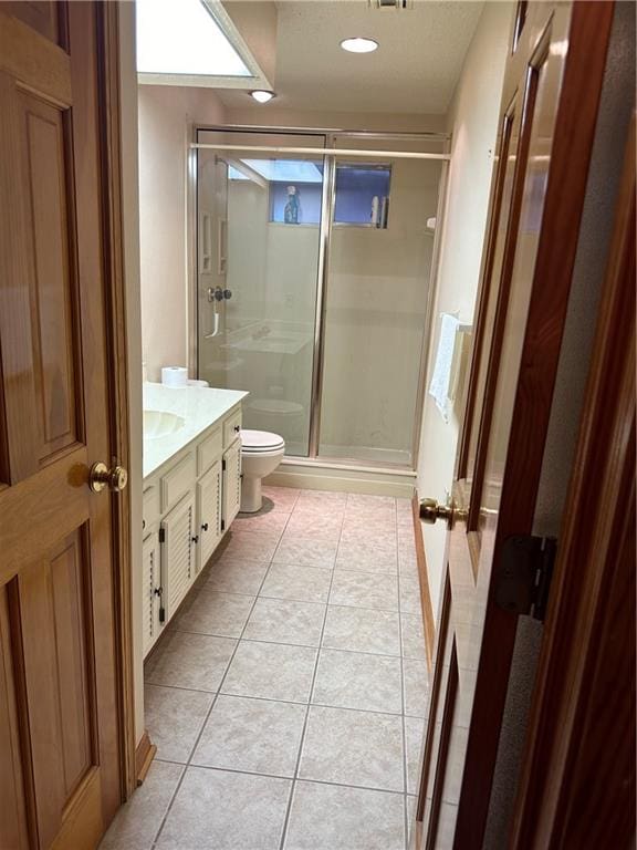 bathroom featuring vanity, toilet, tile floors, and a shower with door