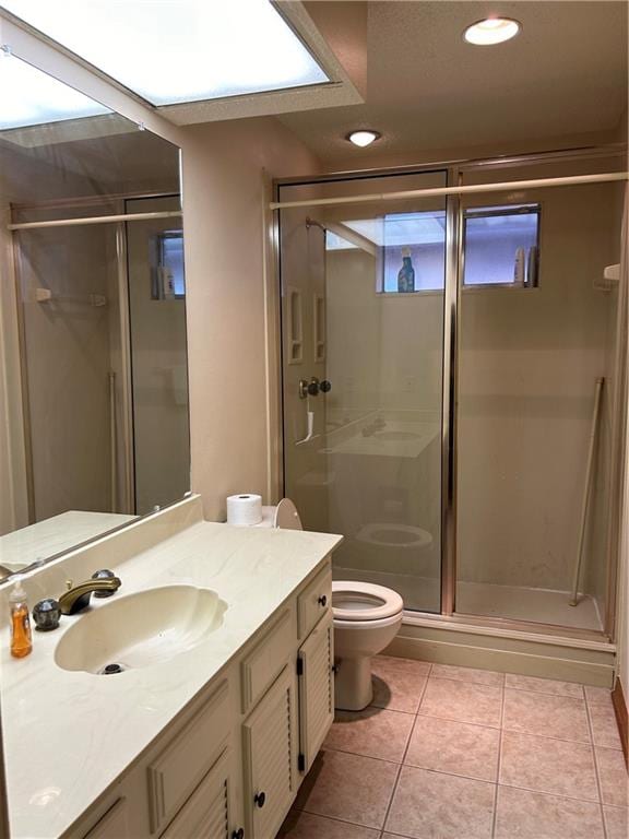 bathroom featuring walk in shower, tile flooring, oversized vanity, and toilet