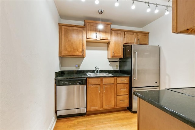 kitchen featuring appliances with stainless steel finishes, sink, light wood-type flooring, decorative light fixtures, and track lighting