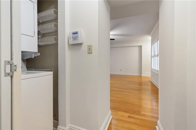 laundry room featuring stacked washer and clothes dryer and light wood-type flooring