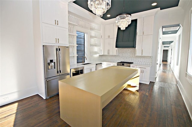 kitchen with hanging light fixtures, appliances with stainless steel finishes, a center island, and dark wood-type flooring