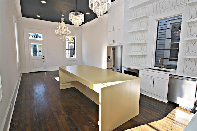 kitchen featuring appliances with stainless steel finishes, a center island, sink, white cabinetry, and hanging light fixtures