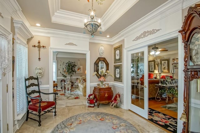 living area featuring ceiling fan with notable chandelier, ornamental molding, light tile floors, and a tray ceiling