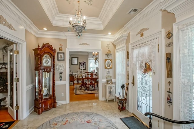 tiled entryway featuring a tray ceiling, an inviting chandelier, and crown molding