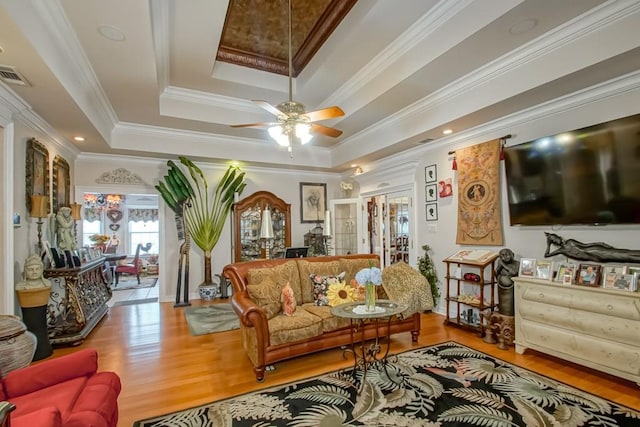 living room featuring ceiling fan, a tray ceiling, hardwood / wood-style floors, crown molding, and french doors