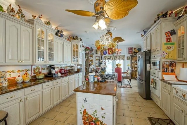 kitchen featuring ceiling fan, light tile floors, oven, stainless steel refrigerator, and decorative light fixtures