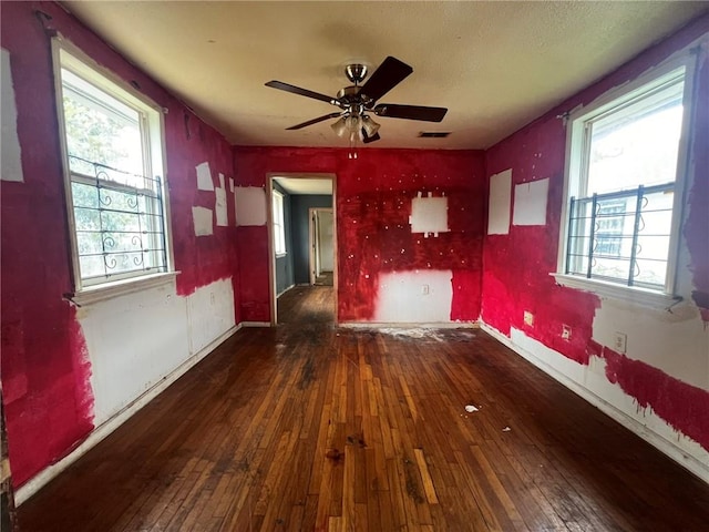 empty room with dark hardwood / wood-style flooring, ceiling fan, and a healthy amount of sunlight