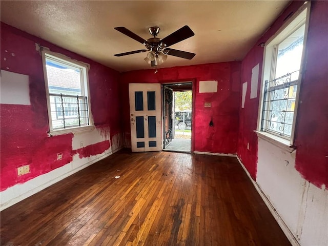 empty room featuring ceiling fan, a wealth of natural light, and dark wood-type flooring