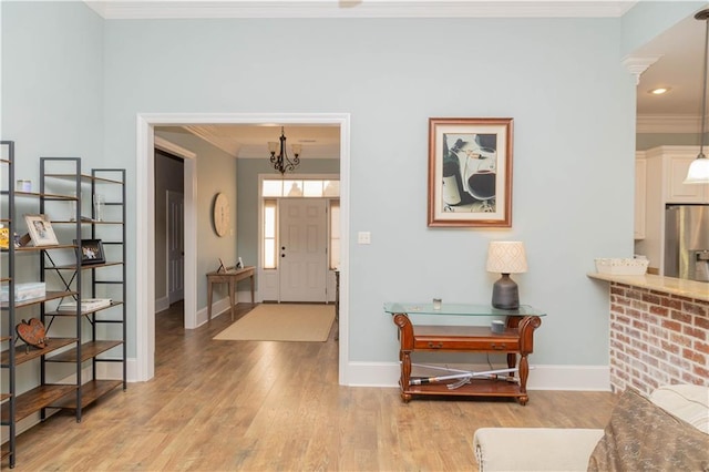 entrance foyer featuring ornamental molding, light hardwood / wood-style floors, and an inviting chandelier