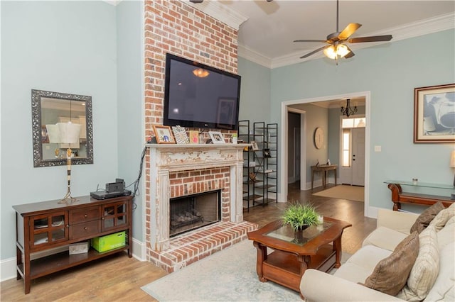 living room featuring ceiling fan, a brick fireplace, wood-type flooring, brick wall, and ornamental molding