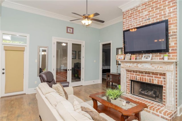 living room with a fireplace, ceiling fan, hardwood / wood-style floors, ornamental molding, and french doors