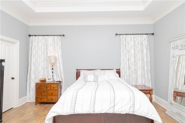 bedroom featuring ornamental molding, light hardwood / wood-style flooring, and a raised ceiling