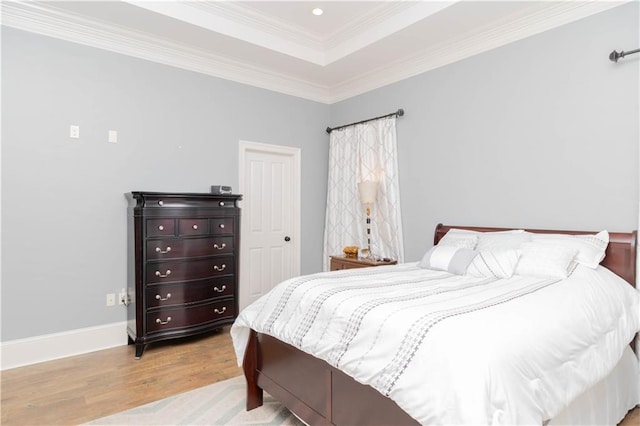 bedroom with hardwood / wood-style floors, a raised ceiling, and crown molding