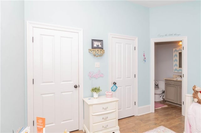 bedroom with ensuite bathroom and light hardwood / wood-style flooring