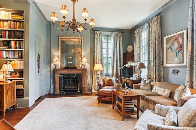 interior space with an inviting chandelier, crown molding, a high end fireplace, built in shelves, and wood-type flooring