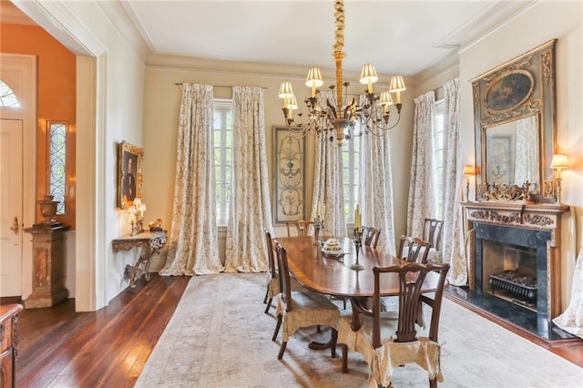 dining room with ornamental molding, an inviting chandelier, dark hardwood / wood-style flooring, and a fireplace