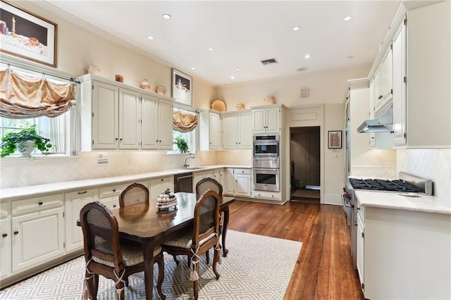 kitchen featuring white cabinets, backsplash, appliances with stainless steel finishes, sink, and wood-type flooring