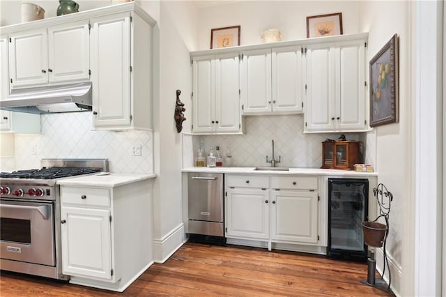 kitchen featuring beverage cooler, appliances with stainless steel finishes, hardwood / wood-style flooring, and white cabinets