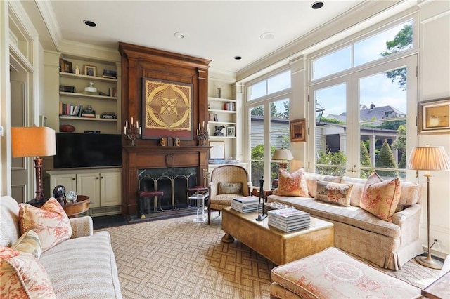 living room featuring built in features, ornamental molding, french doors, and a fireplace