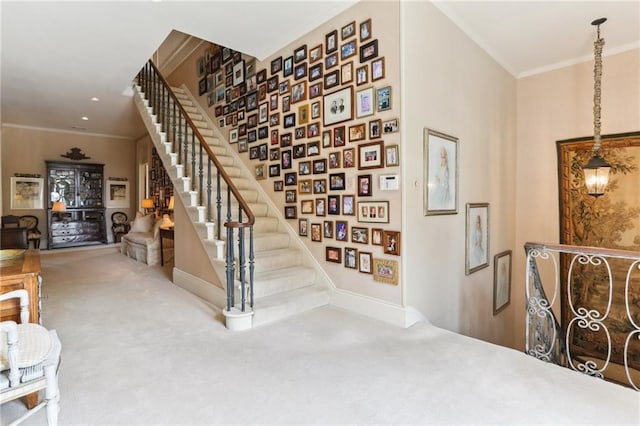 staircase with ornamental molding, a notable chandelier, and carpet flooring