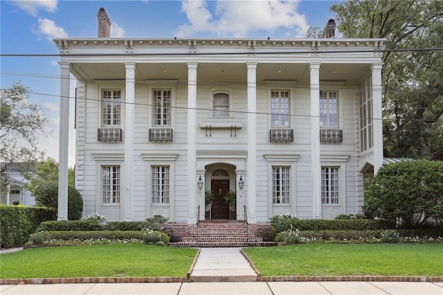 view of front of property with a balcony and a front yard