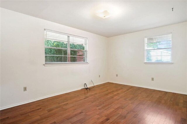 empty room with a healthy amount of sunlight and dark hardwood / wood-style floors