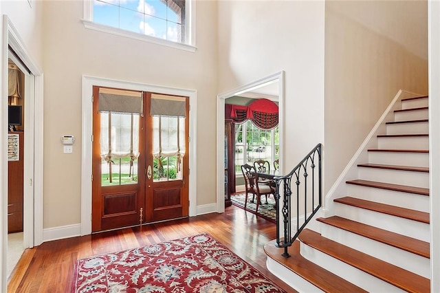 foyer entrance with a towering ceiling, hardwood / wood-style flooring, and french doors