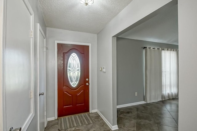 foyer with dark tile flooring and a textured ceiling