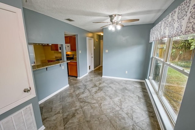 unfurnished dining area featuring a textured ceiling, ceiling fan, and tile floors