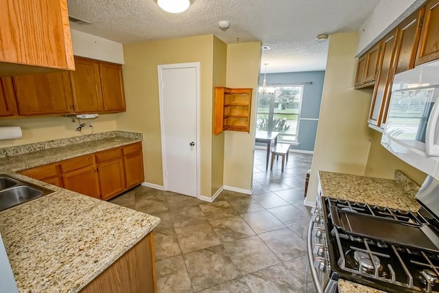 kitchen with a notable chandelier, a textured ceiling, light tile flooring, and light stone counters