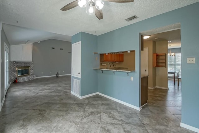 2545 Kismet St, Marrero, LA 70072 - kitchen with a ceiling fan, a breakfast bar area, a textured ceiling, baseboards, and a fireplace