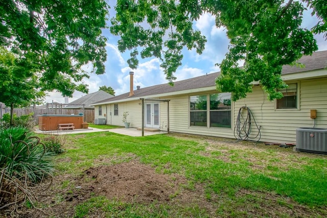 back of property featuring a lawn, a patio area, central AC unit, and a hot tub