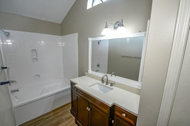 bathroom with shower / tub combination, wood-type flooring, vaulted ceiling, and vanity with extensive cabinet space