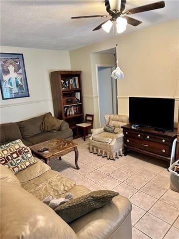 living room with ceiling fan, a textured ceiling, and light tile flooring