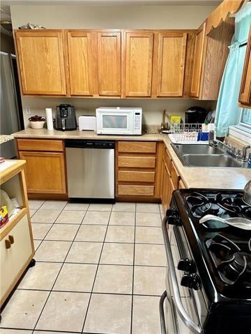 kitchen featuring appliances with stainless steel finishes, sink, and light tile floors