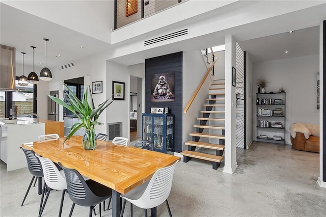 dining area with concrete floors and a towering ceiling